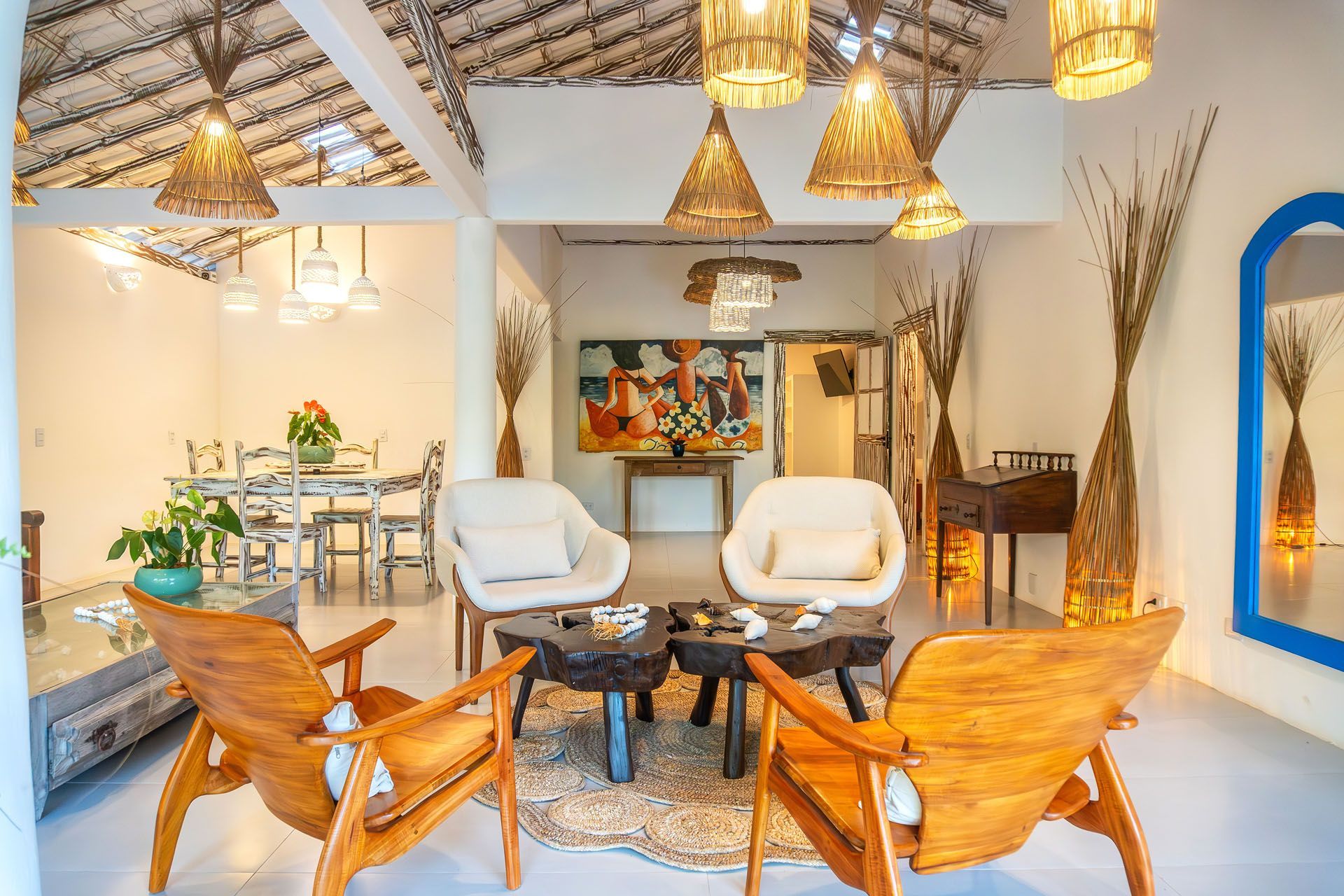 Sala de estar moderna e iluminada com cadeiras brancas, sofás de madeira, luminárias pendentes e uma lareira decorativa.