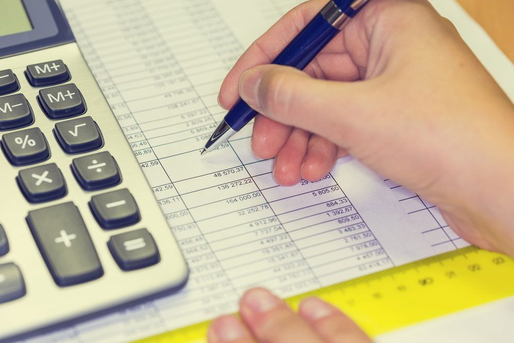 Hand Writing on Financial Document Next to a Calculator and Ruler — NR Bookkeeping in Goonellabah, NSW