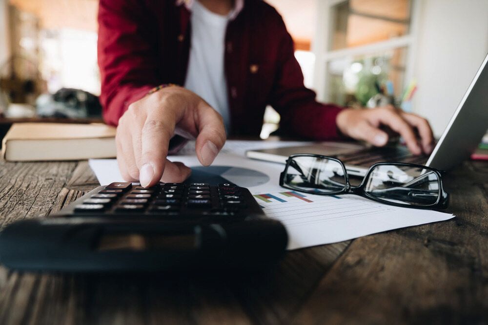 Person Using a Calculator and Laptop on a Wooden Table — NR Bookkeeping in Lismore, NSW