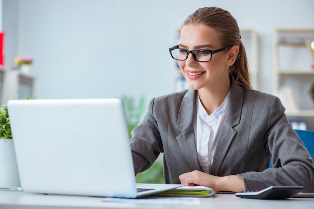 Woman in Glasses Smiles While Working on Laptop at Desk — NR Bookkeeping In Alstonville, NSW