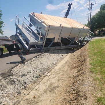 A man is pushing a large container down a dirt road