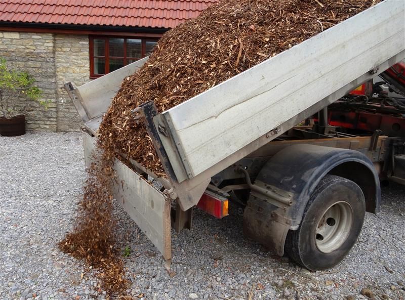 A wheelbarrow filled with dirt and a shovel in a garden