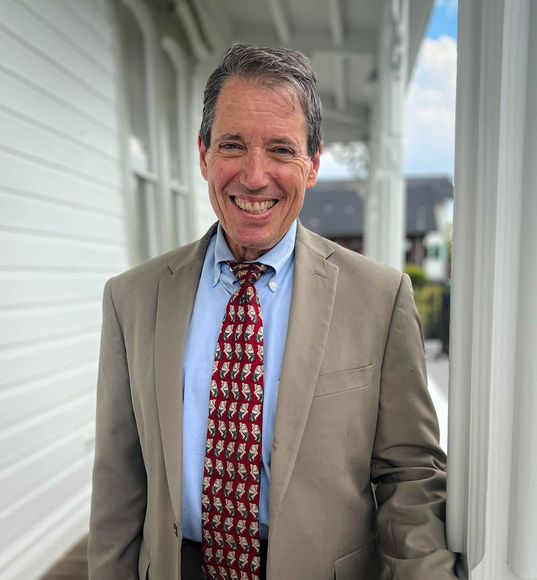 A man in a suit and tie is smiling for the camera