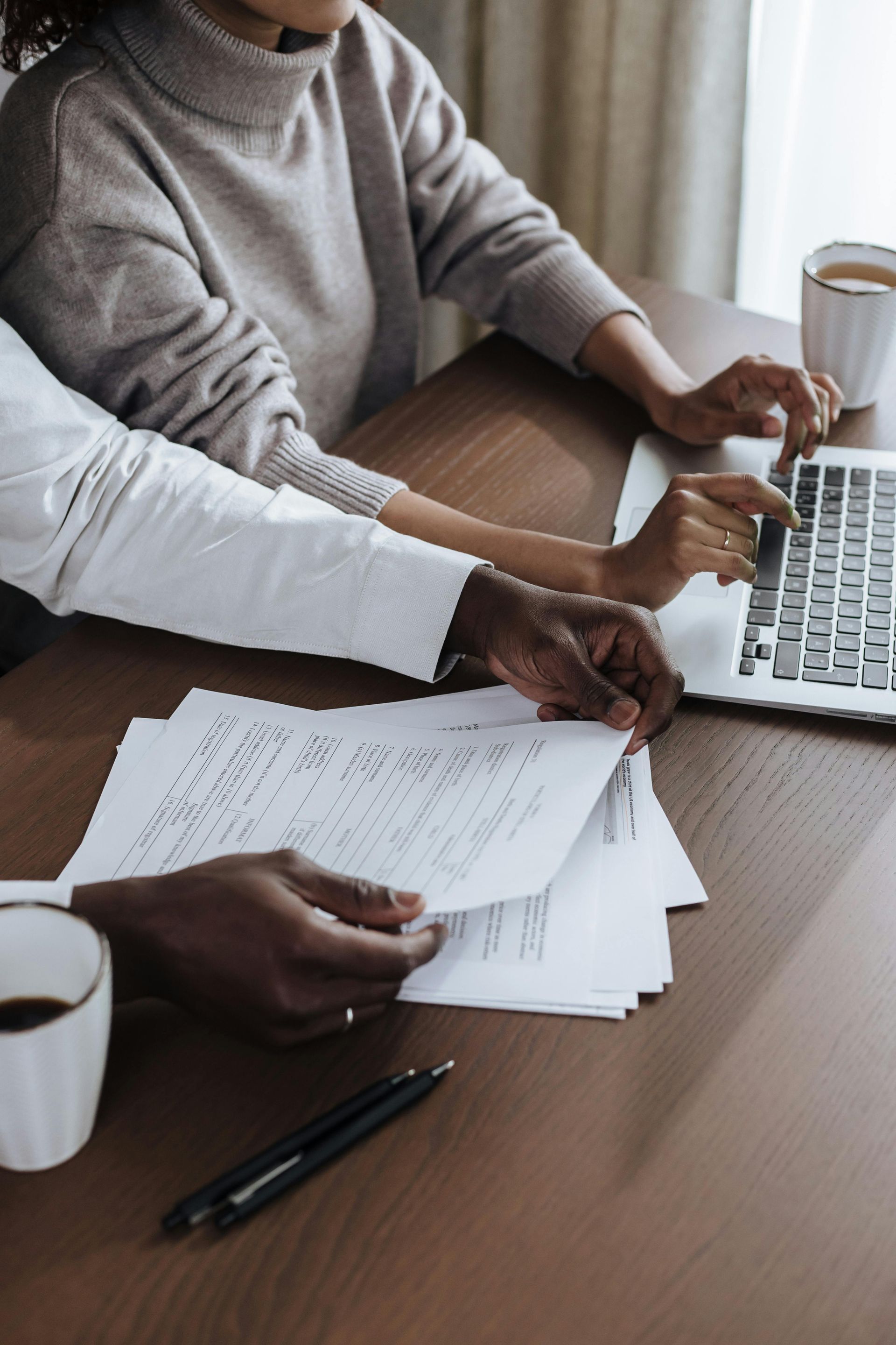 A man and a woman are sitting at a table with papers and a laptop.