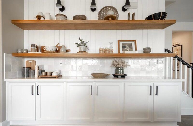 A kitchen with white cabinets and wooden shelves.
