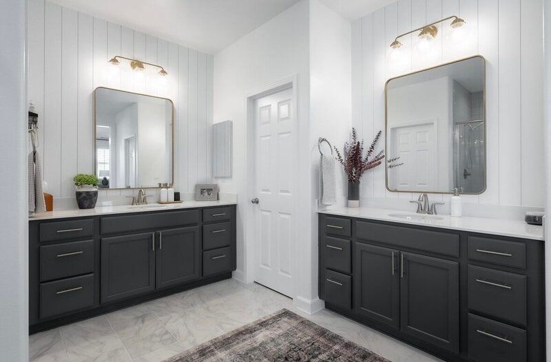 A bathroom with two sinks , two mirrors , and a rug.