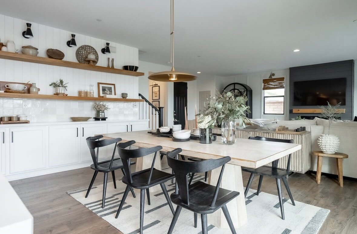 A dining room table with black chairs in a living room.