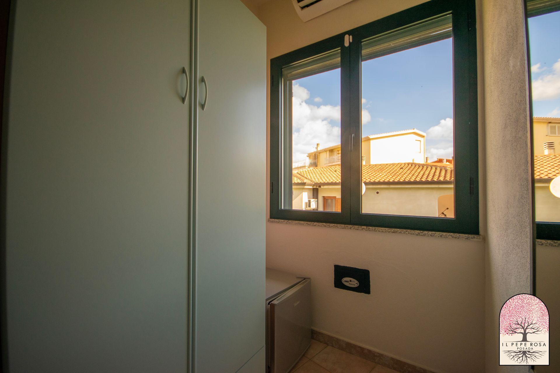 Una stanza con una grande finestra e un armadio bianco