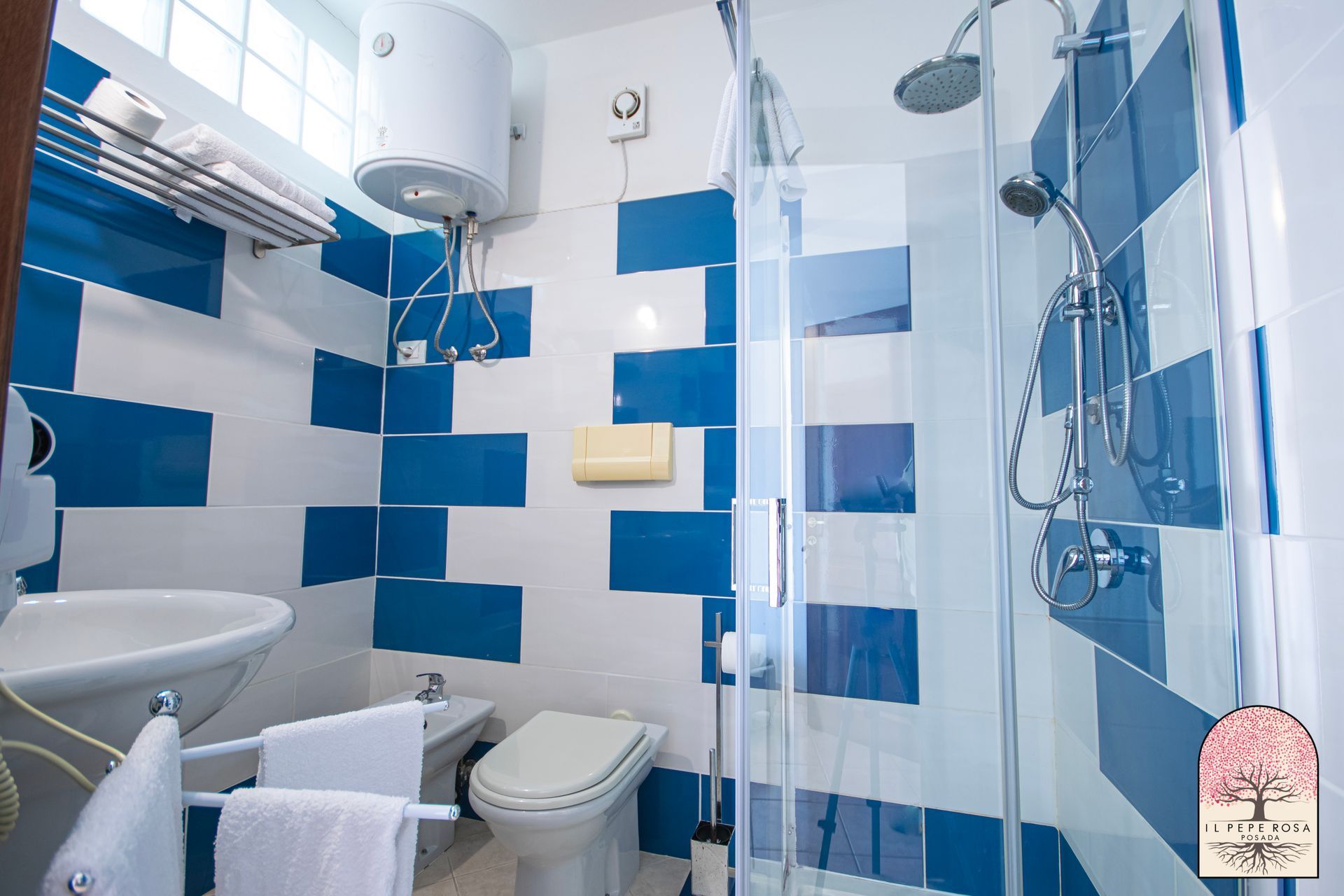 Un bagno con piastrelle blu e bianche, un water, un lavandino e una doccia.