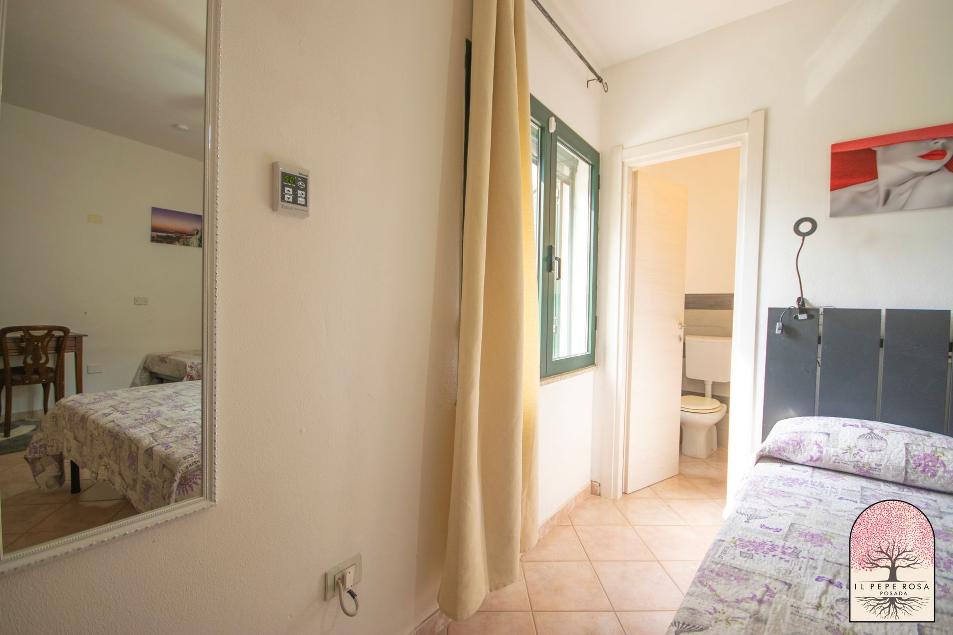 Una camera da letto con un letto, uno specchio, un bagno e una finestra.