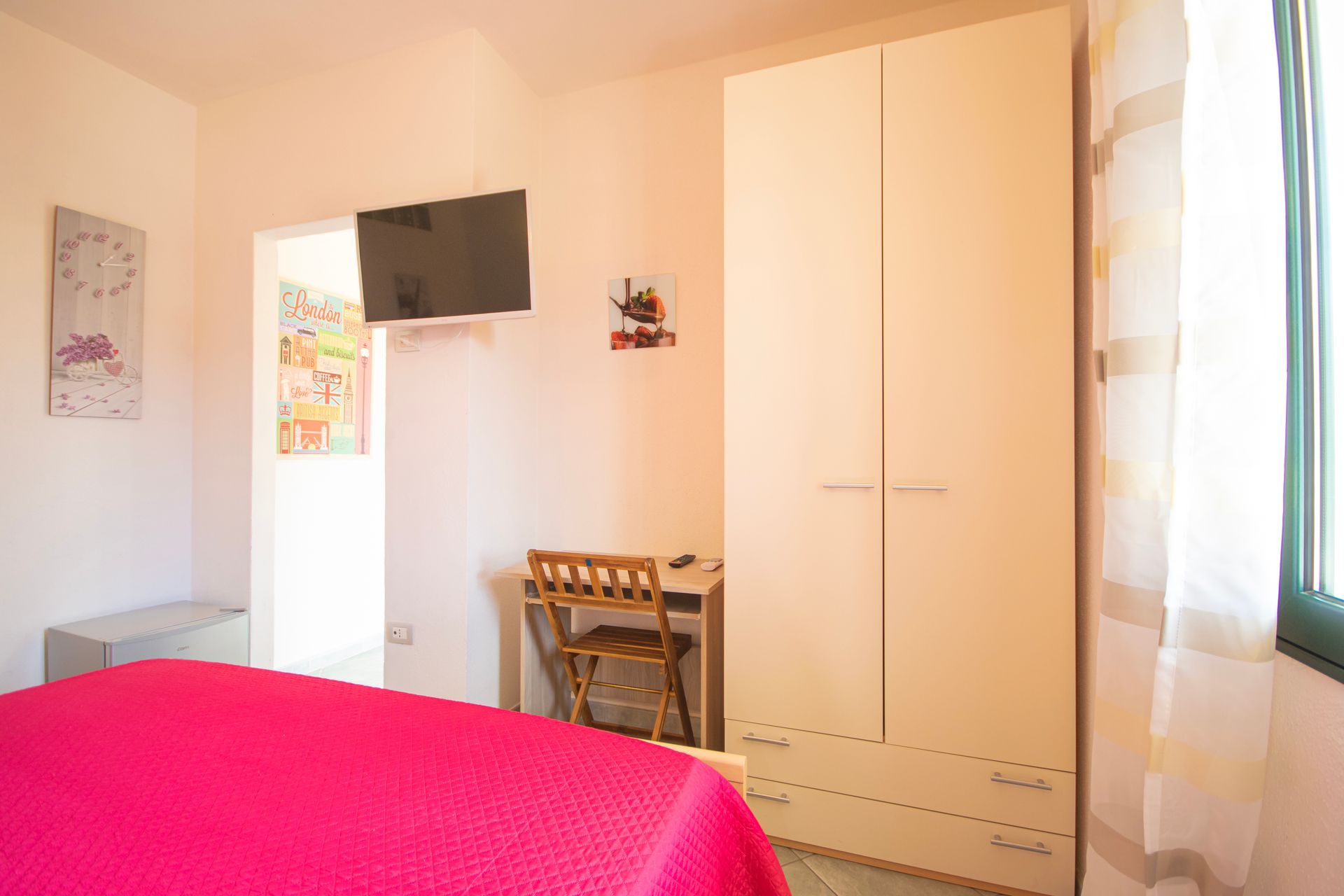 Una camera da letto con un letto, una scrivania, un armadio e una televisione.