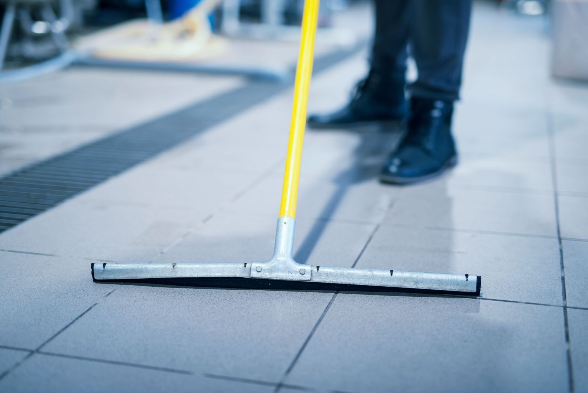 A person is cleaning a tiled floor with a mop.