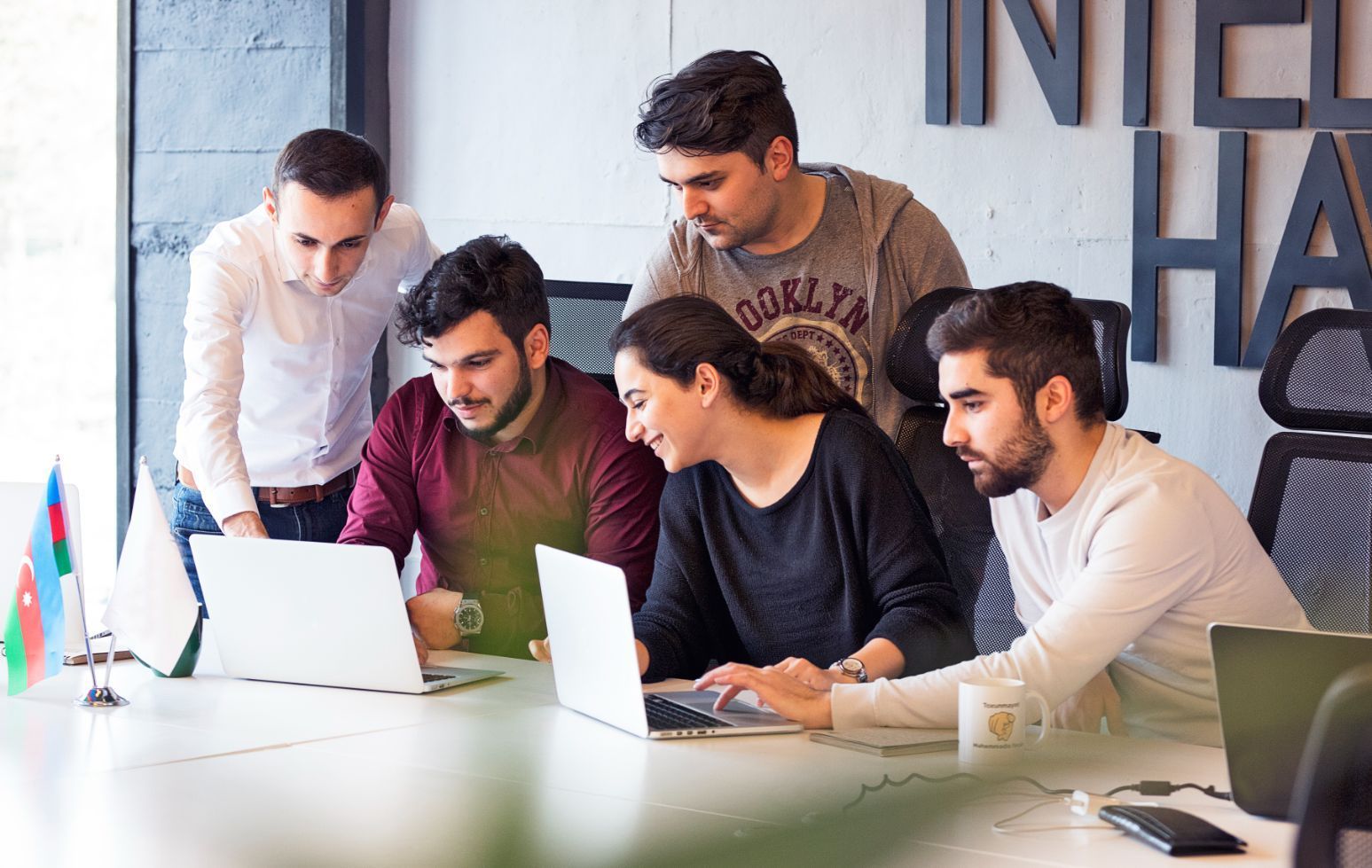 A group of people are sitting around a table looking at laptops.