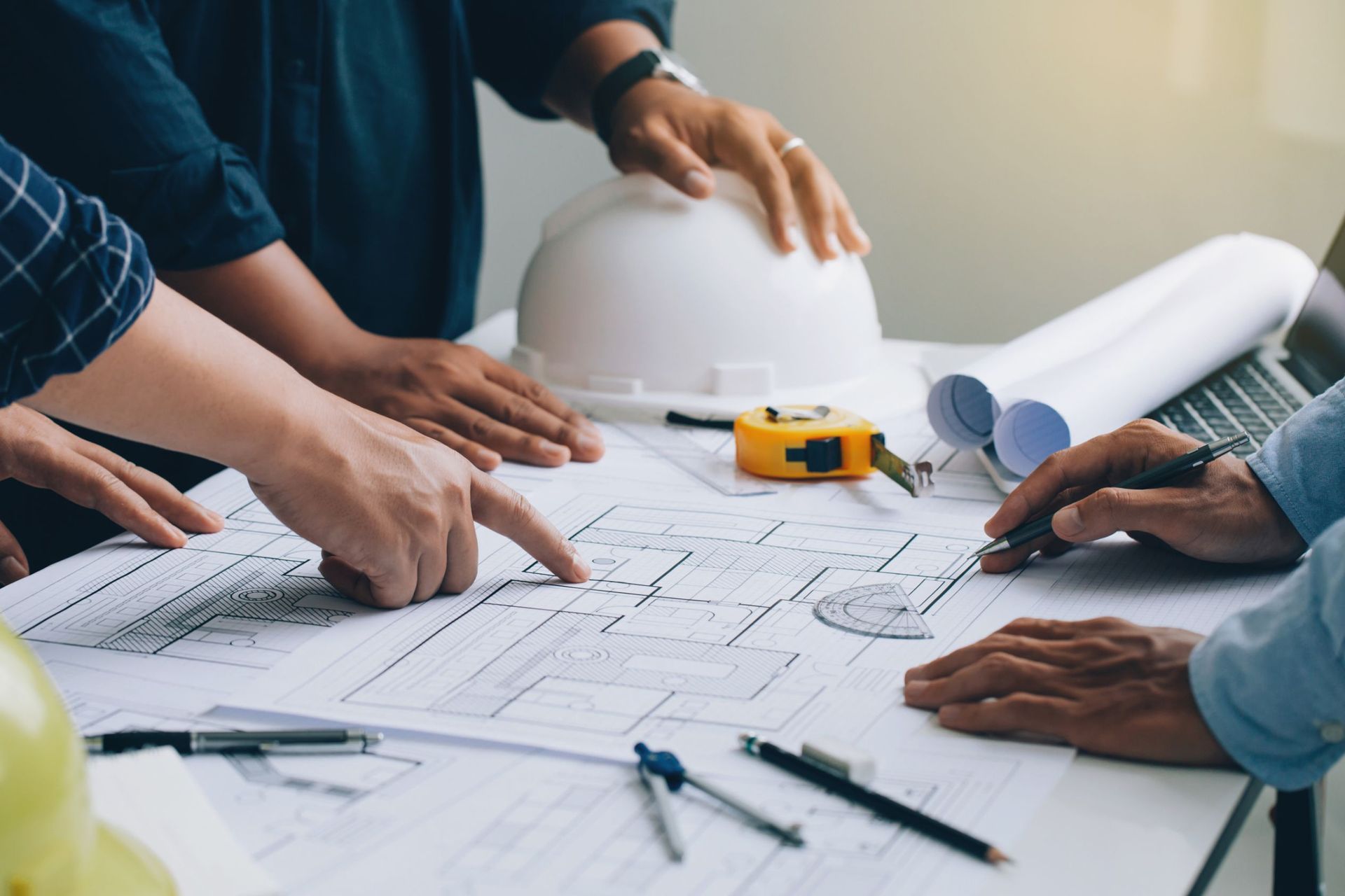 A group of people are sitting around a table looking at a blueprint.