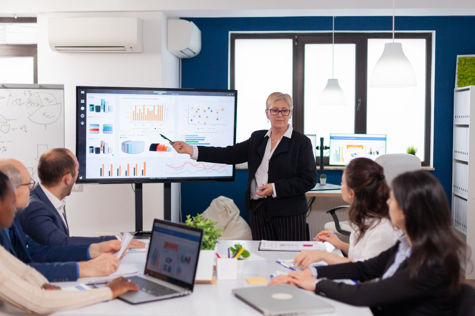 A woman is giving a presentation to a group of people in a conference room.