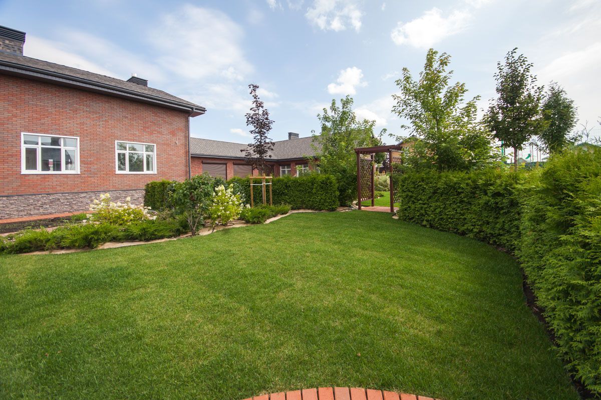 A brick house with a large lush green lawn in front of it.