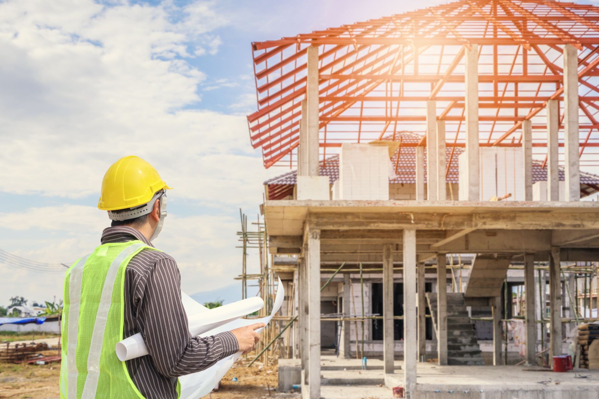 A construction worker is looking at a blueprint at a construction site.