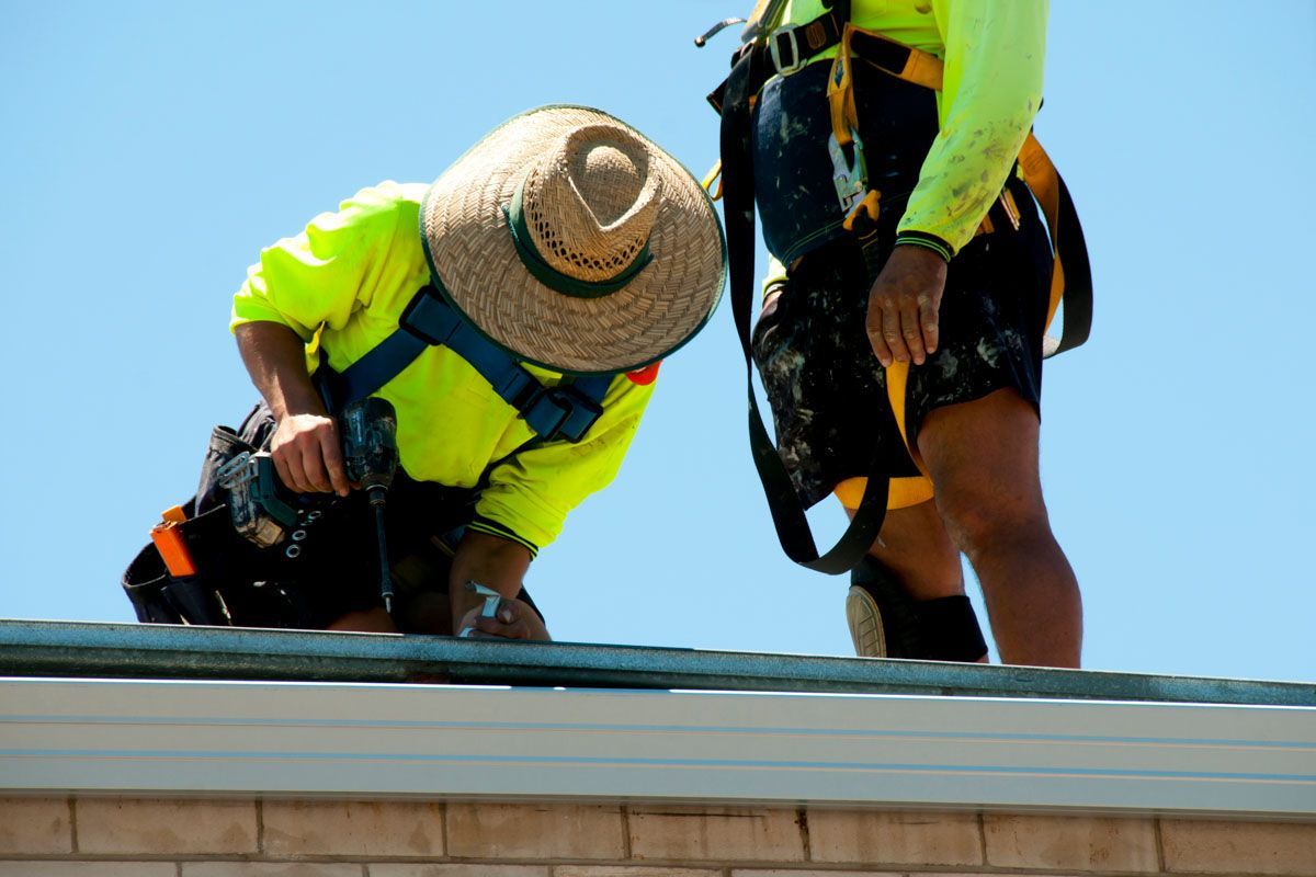 Two construction workers are working on the roof of a building.