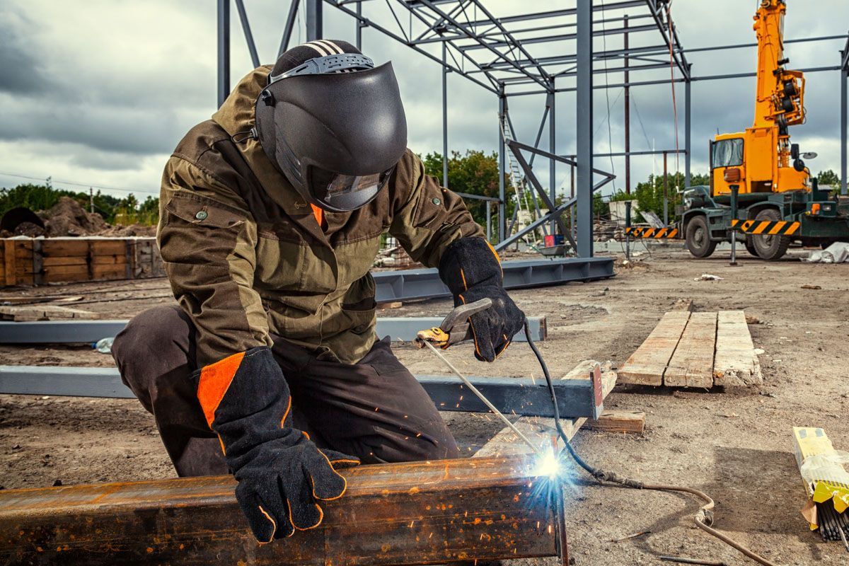 A man is welding a piece of metal on a construction site.