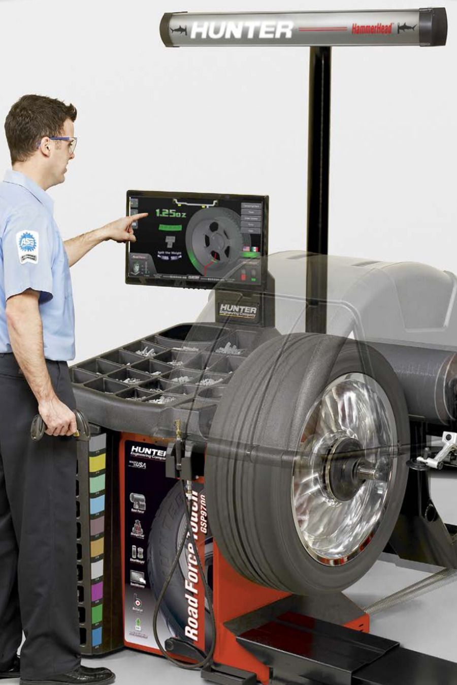 Mechanic balances a tire on a Hunter Road Force balancer, using the touch screen interface.