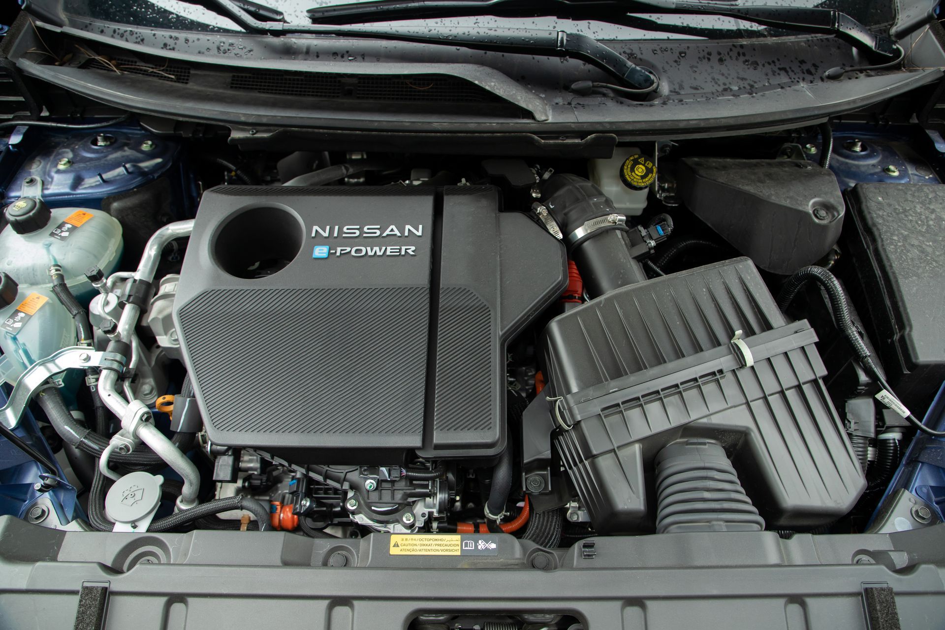 The engine of a nissan leaf is shown with the hood open.