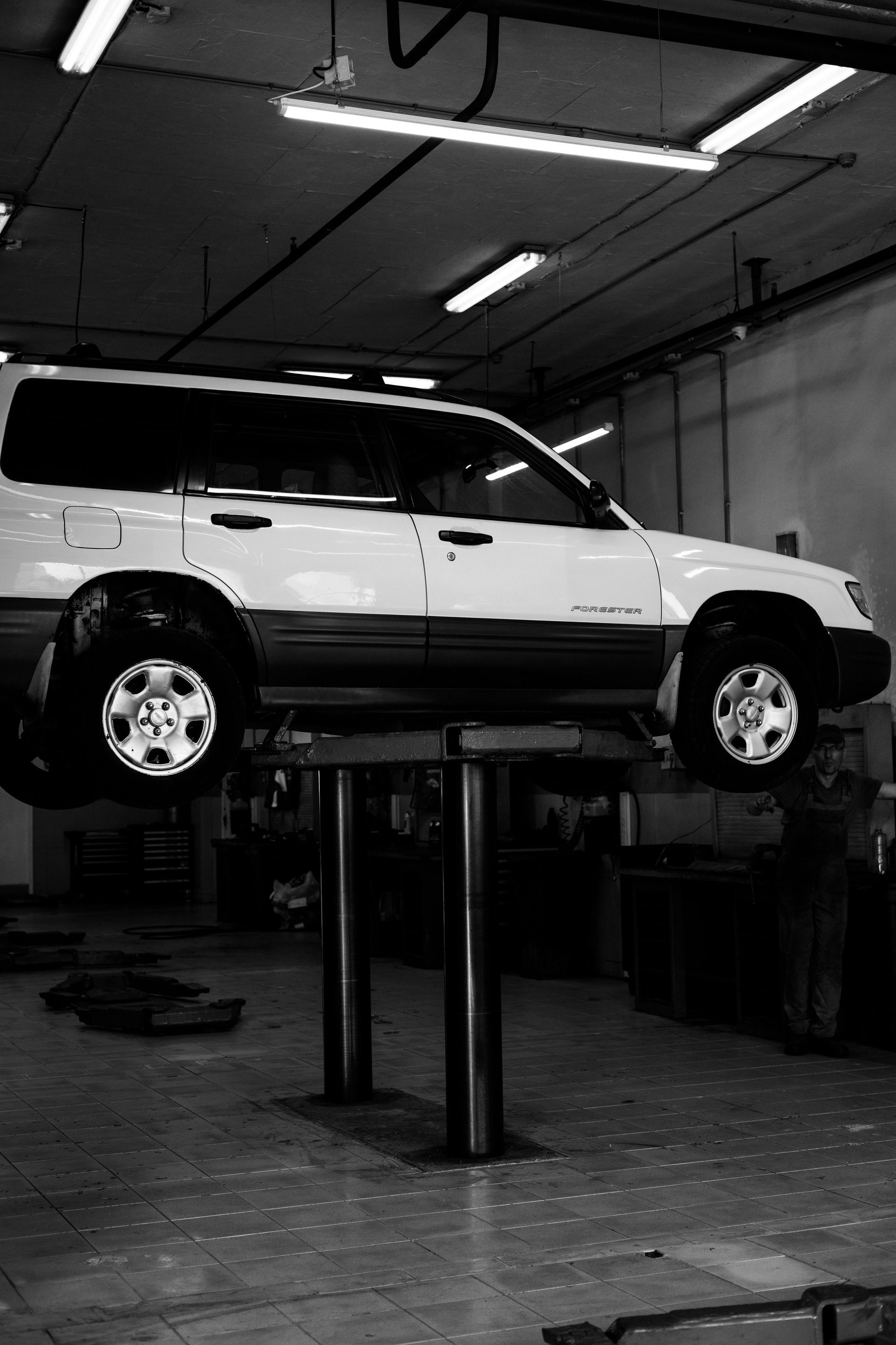 A white suv is sitting on a lift in a garage.