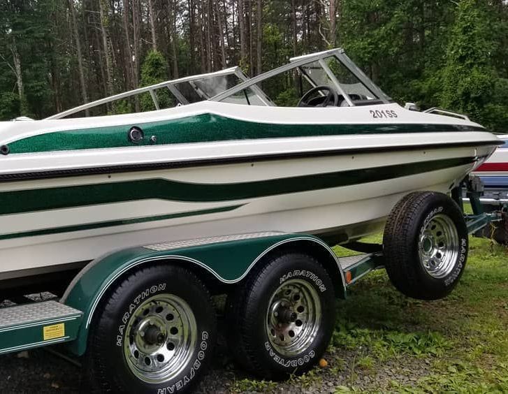 A white and green boat is parked on a trailer.