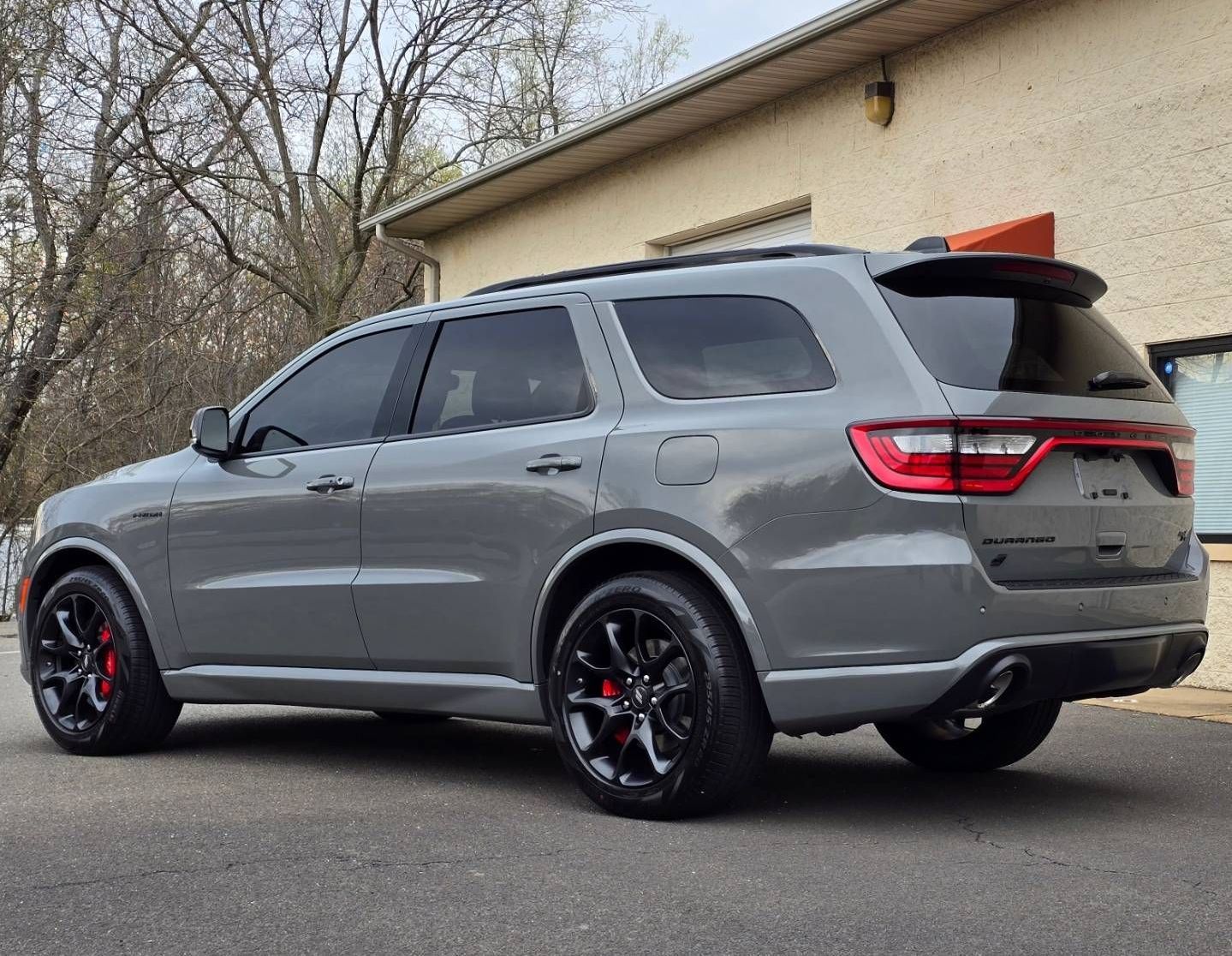 A gray dodge durango is parked in front of a building.