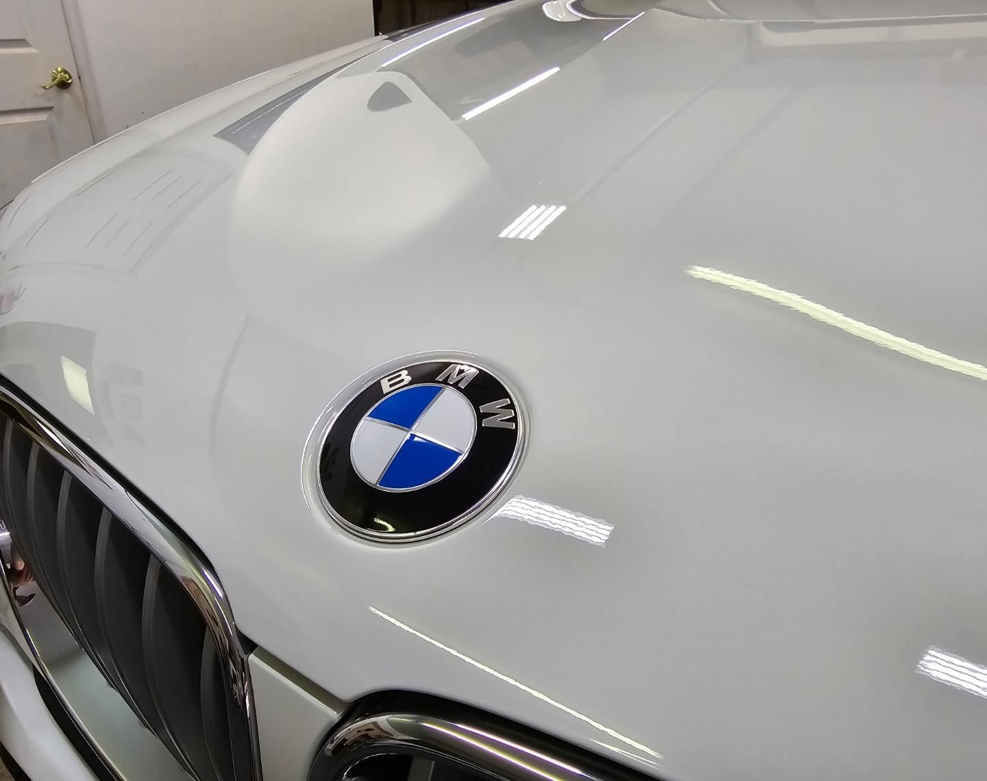 A white bmw with a blue and white bmw logo on the hood