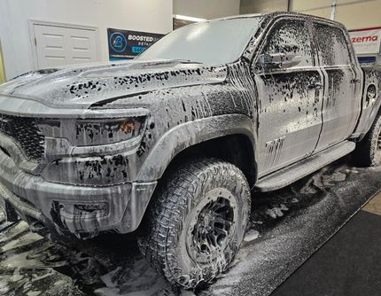 A truck is covered in foam and is sitting on a concrete surface.