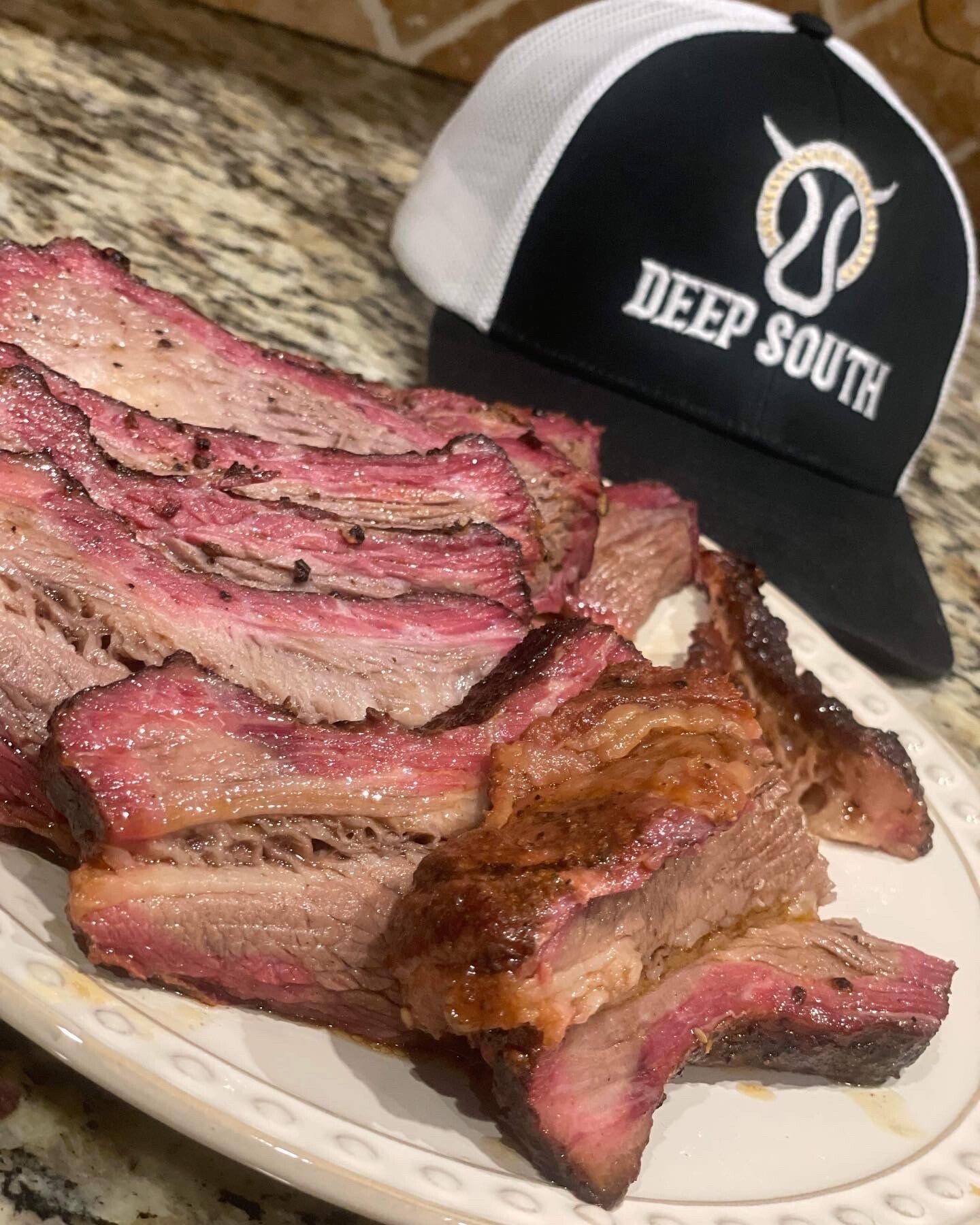 A plate of meat next to a hat that says deep south