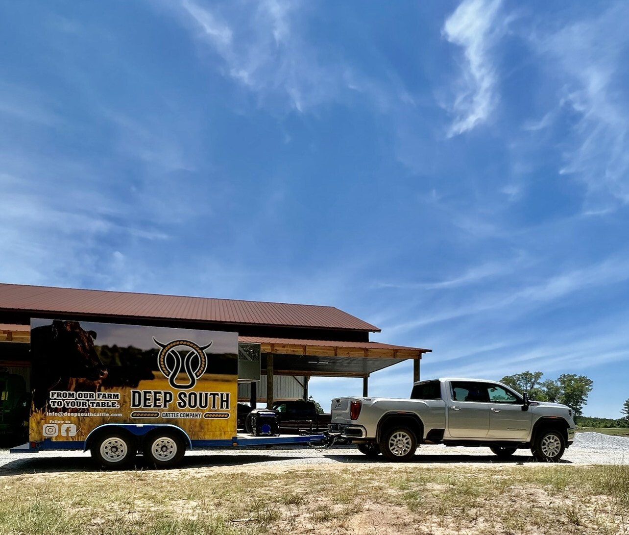 A truck with a trailer attached to it is parked in front of a building.