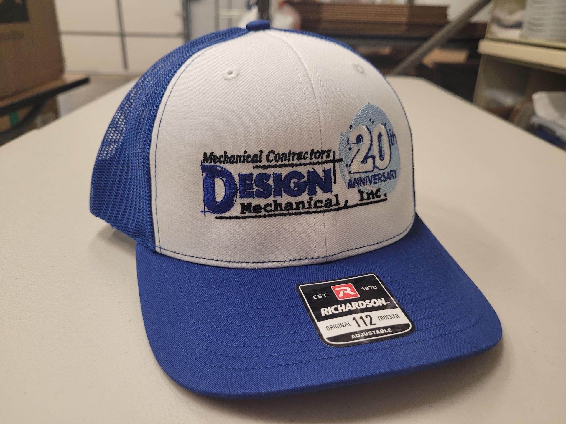 A blue and white hat with the word design on it