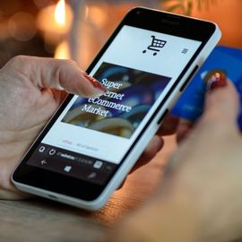 A person holding a cell phone that says super market ecommerce market