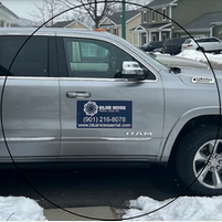 A silver car with a blue sticker on the door that says blue house