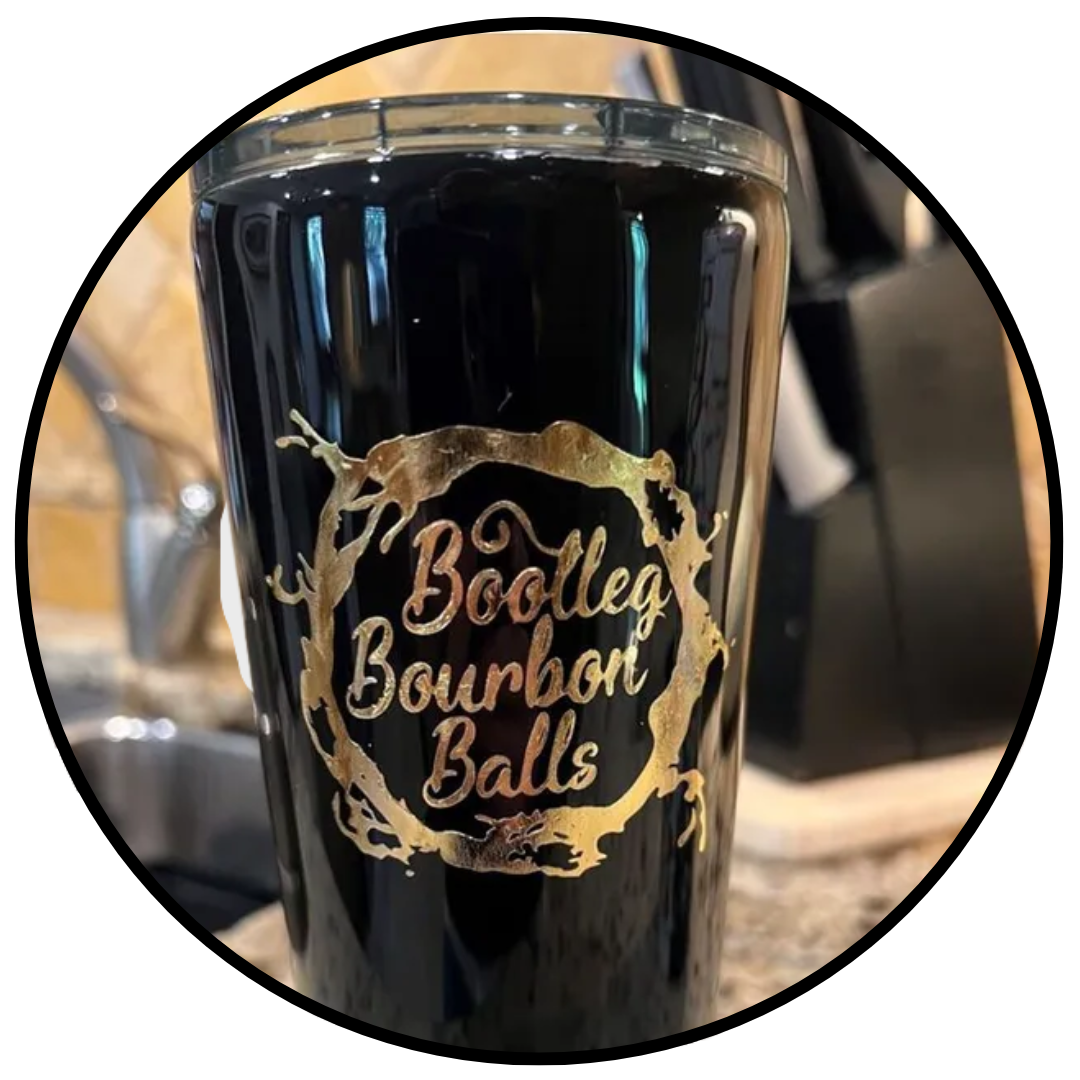 A black tumbler with the words `` bootleg bourbon balls '' on it is sitting on a counter.