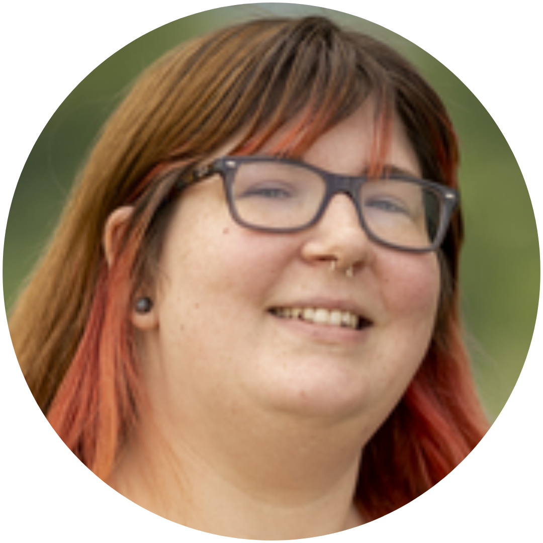 A woman with red hair and glasses is smiling in a circle