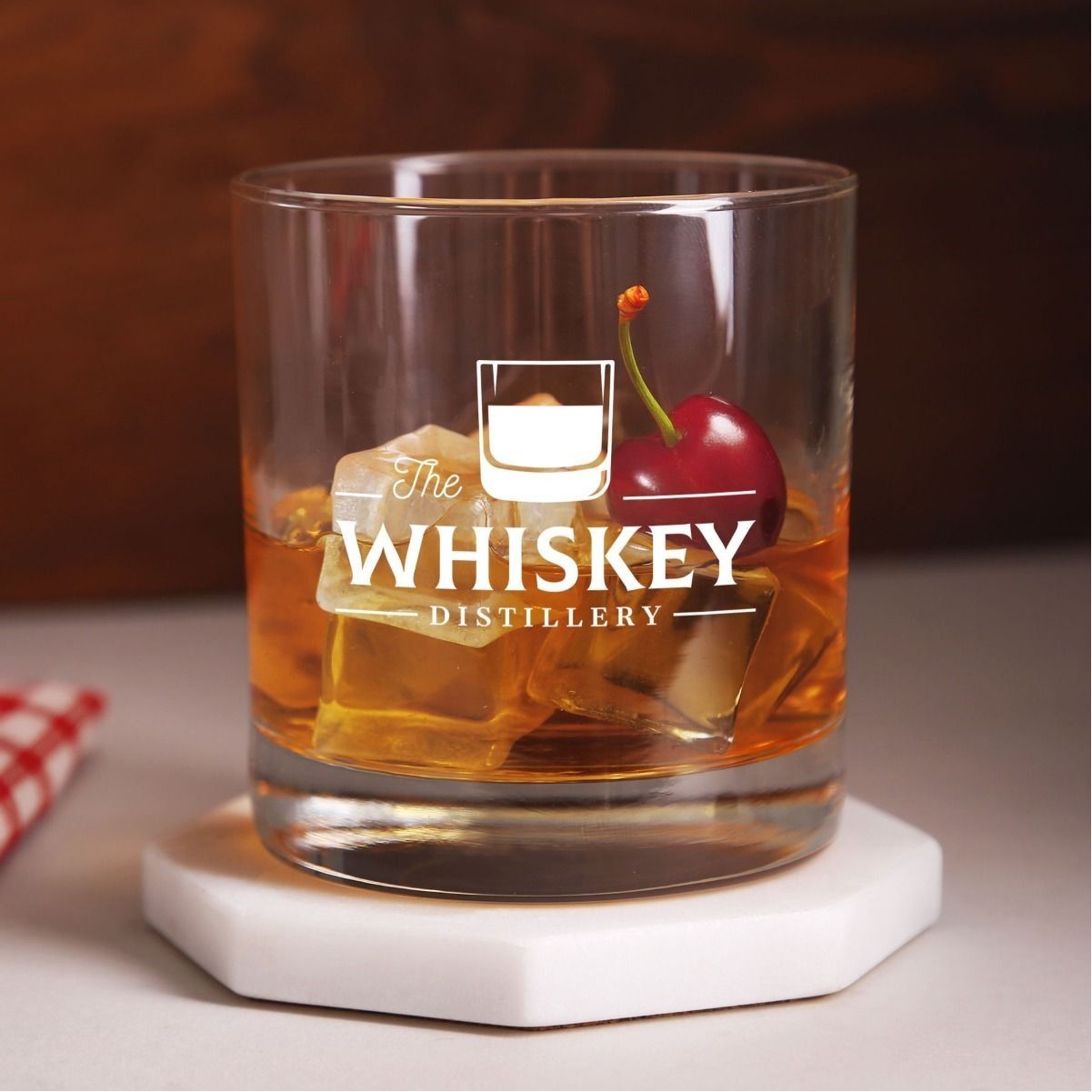 A glass of whiskey with ice and a cherry on top