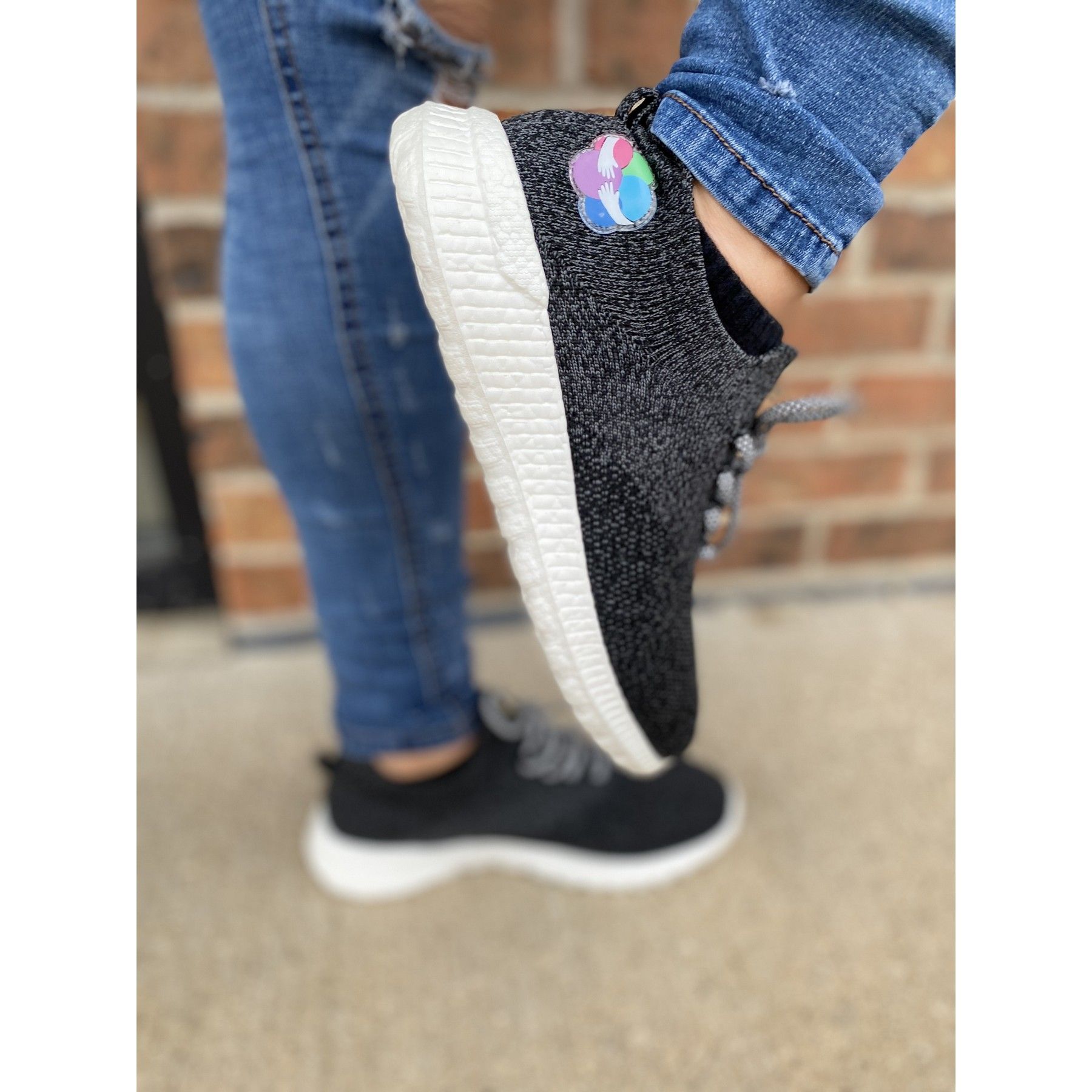 A close up of a person wearing a pair of black sneakers.