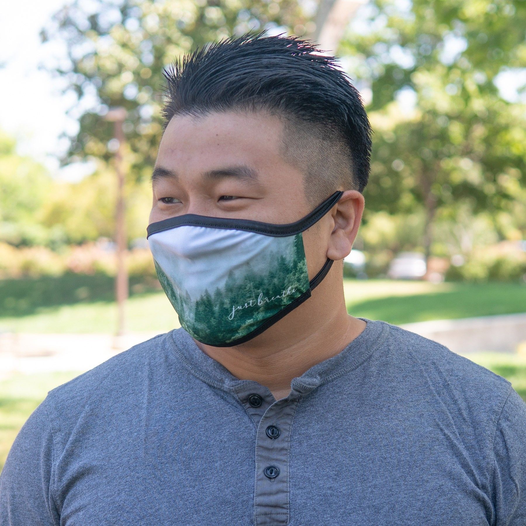 A man wearing a face mask with a picture of trees on it.