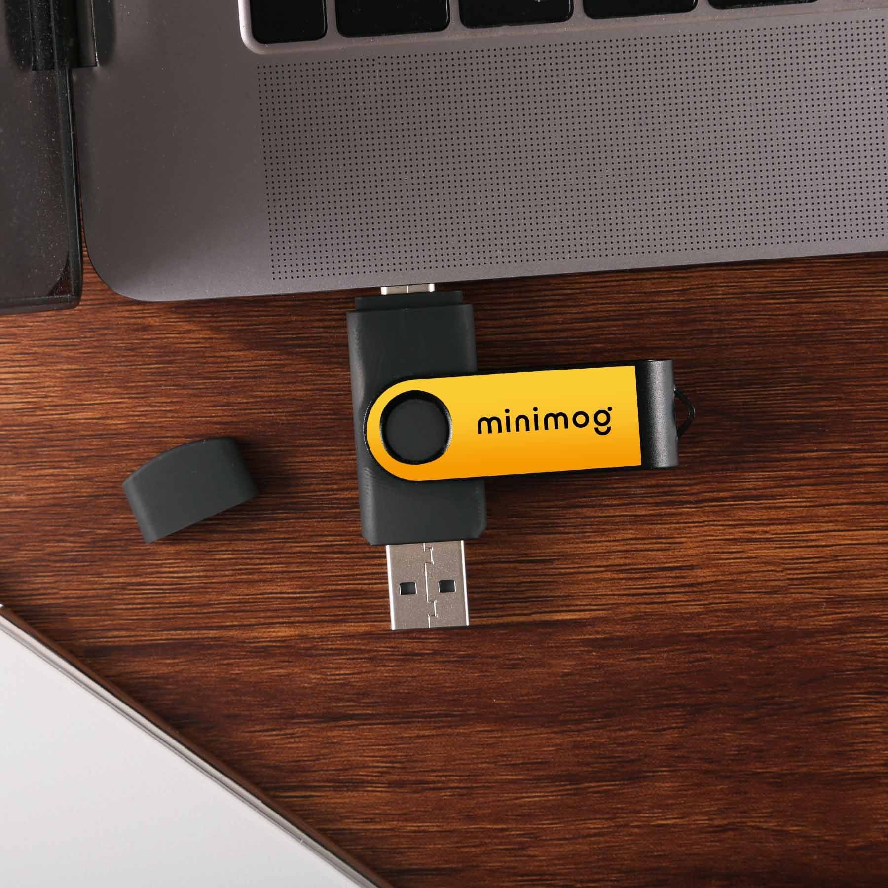 A yellow minimog flash drive is sitting next to a laptop