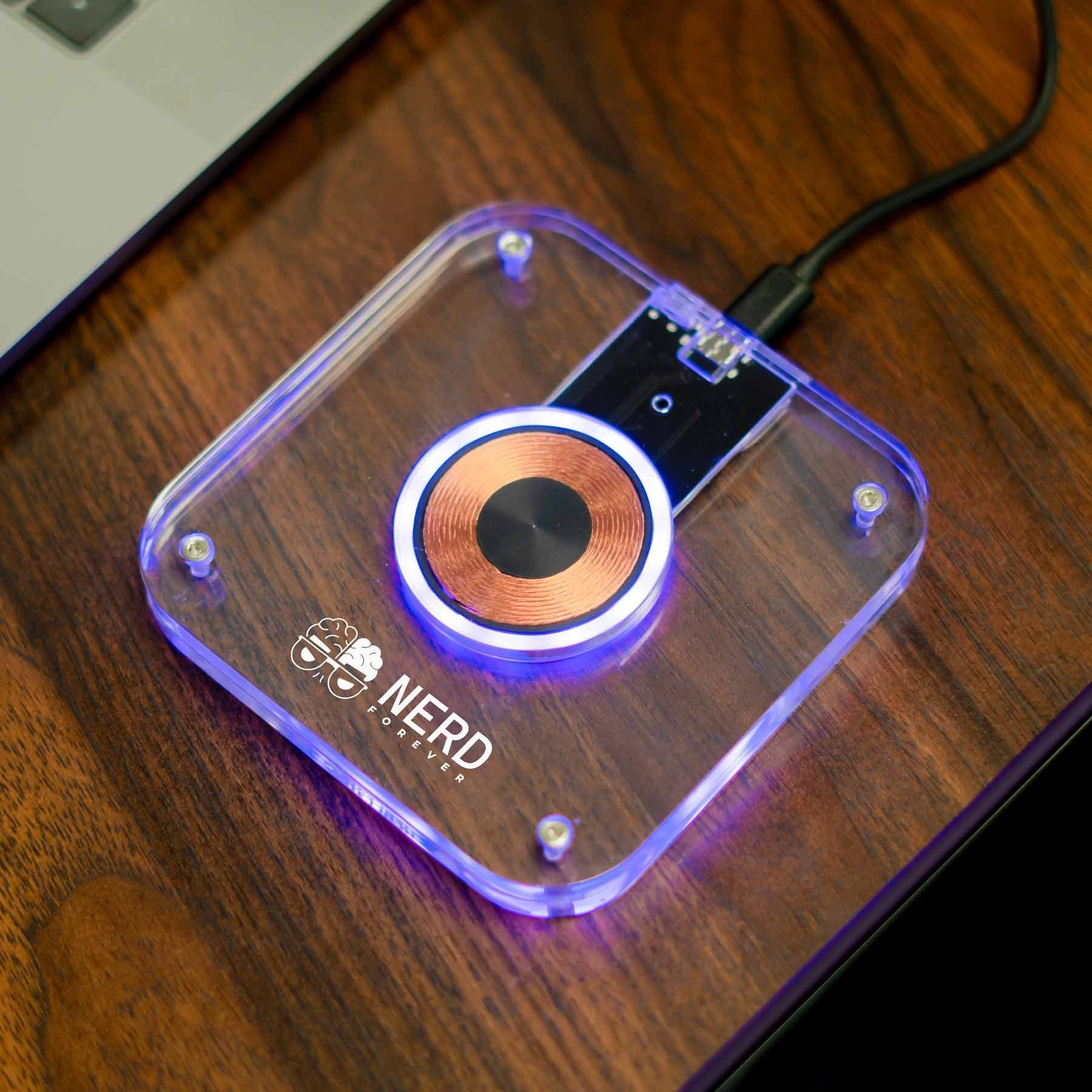A nerd wireless charger is sitting on a wooden table next to a laptop