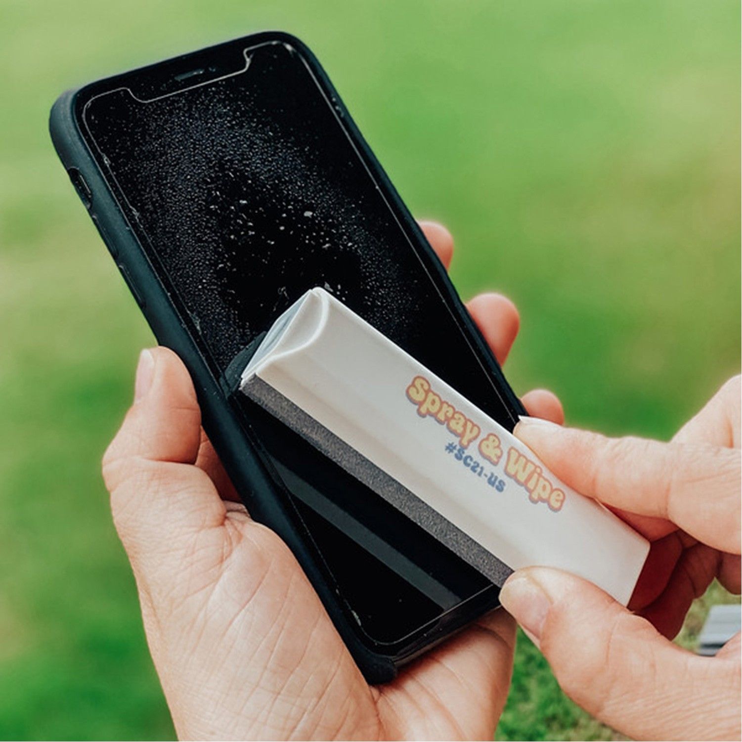 A person is holding a cell phone with a spray and wipe on it