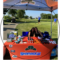 Two women are sitting at a shamrock table in front of a golf course.