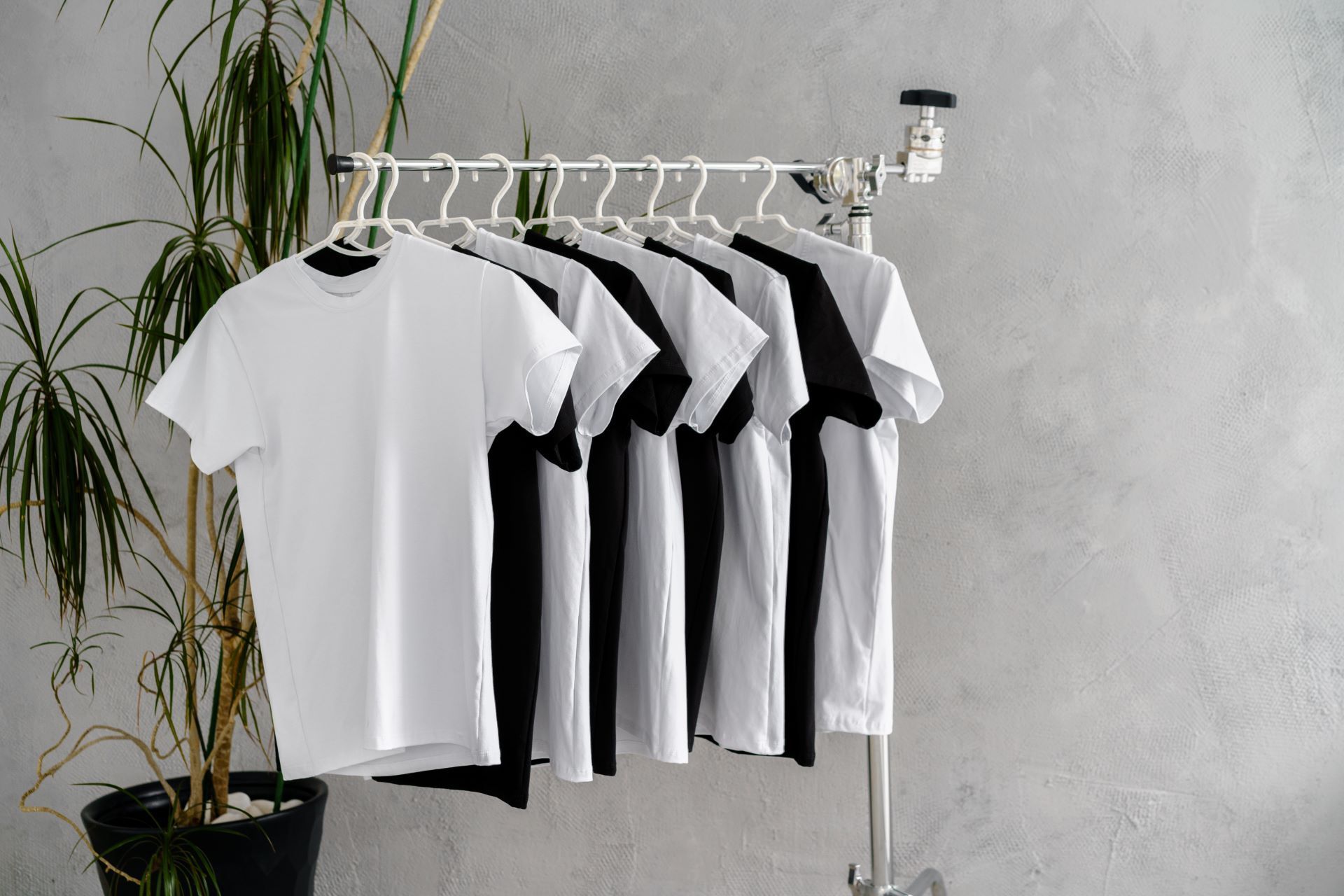 A row of white and black t-shirts hanging on a rack.
