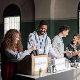 A group of people are standing around a table with donation boxes.