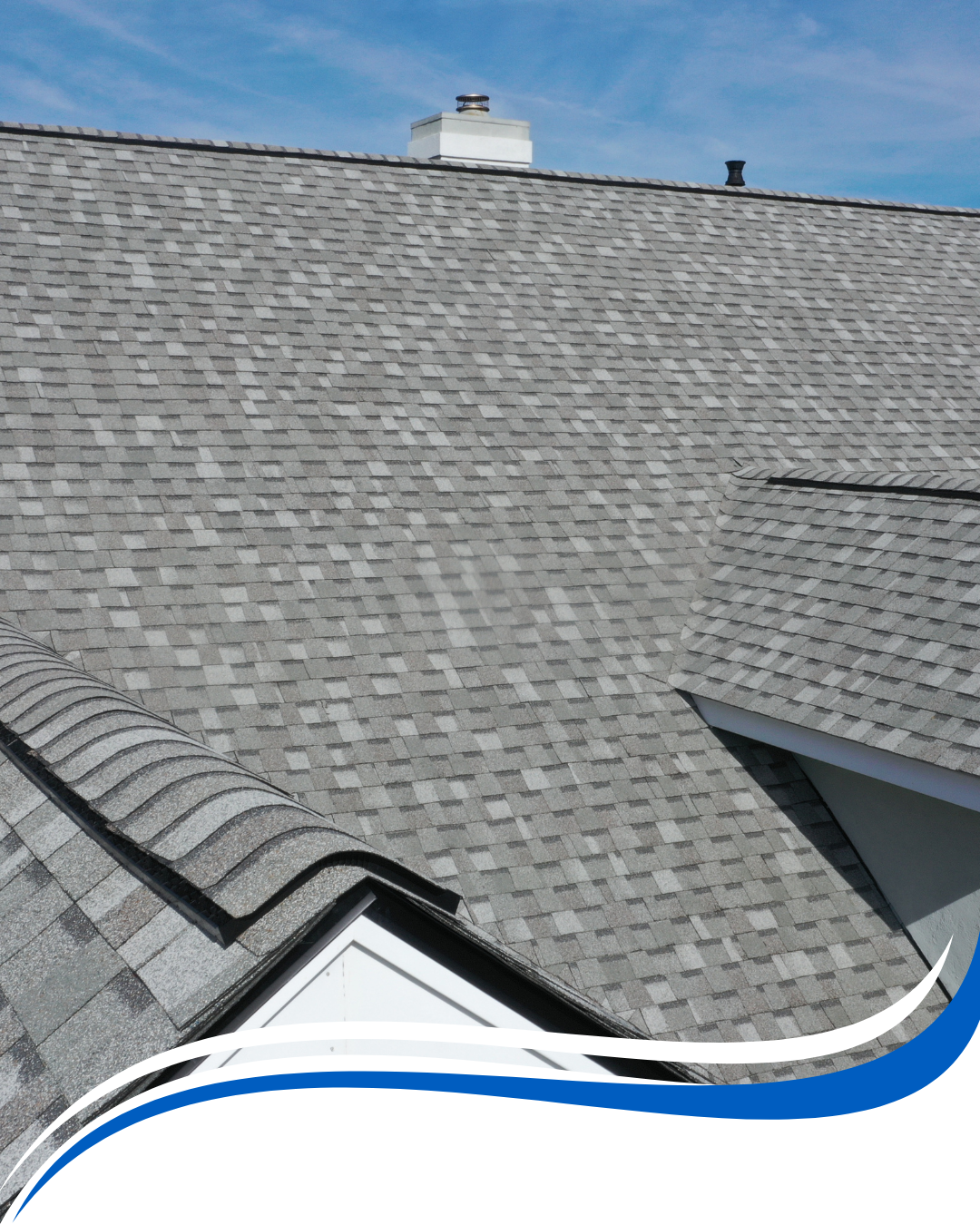 Gray shingle roof on a house with a chimney, against a blue sky.