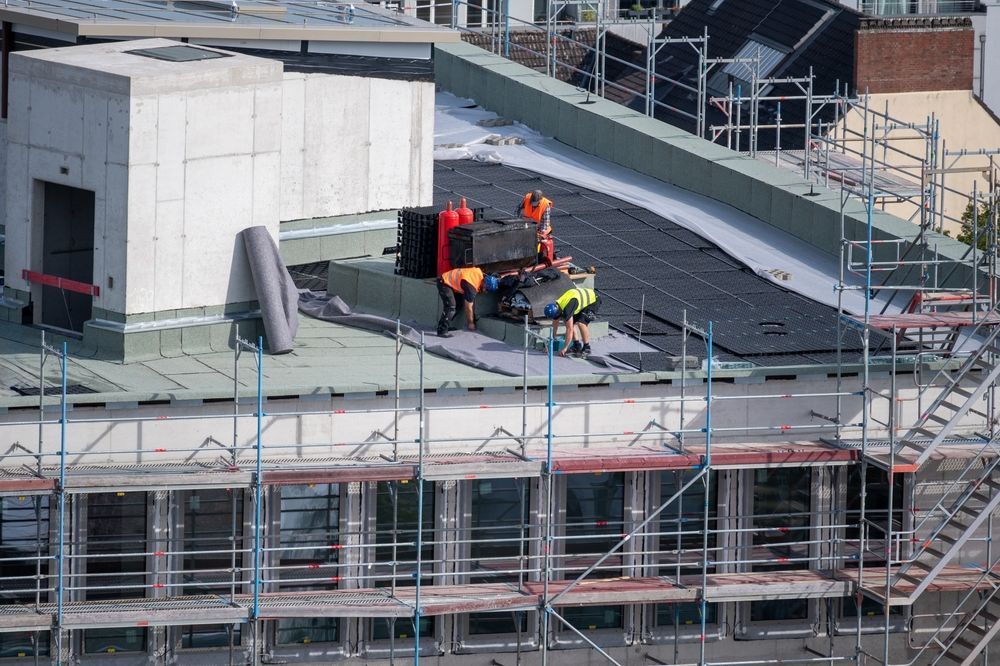 Construction workers on a building roof, installing roofing material.