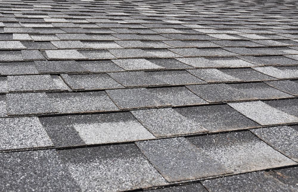 Close-up of a gray asphalt shingle roof, angled perspective showing overlapping tiles.