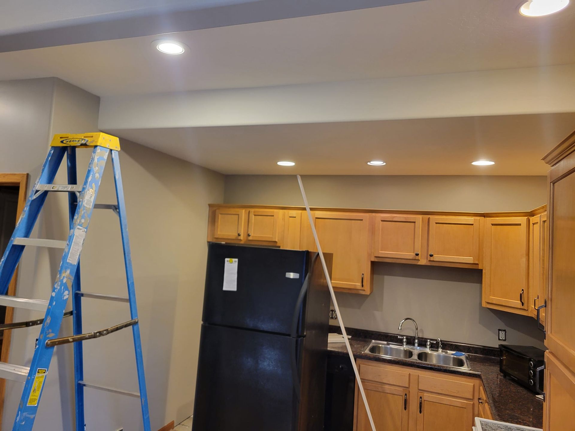 A Blue Ladder Is Sitting In A Kitchen Next To A Black Refrigerator – Cottage Grove, MN - Minnesota Nice Painting